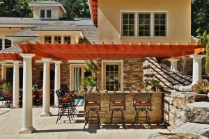 Teakwood Builders of Saratoga Springs built this spectacular poolside patio in Albany with a natural stone bar and water features